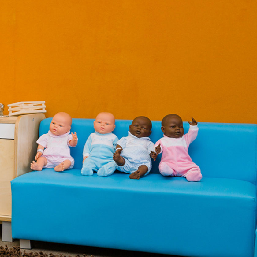 Baby dolls sitting on a blue couch at Spotted Frog Preschool