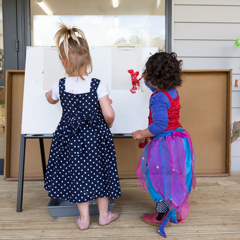 Two little girls painting on an easel at Spotted Frog Preschool