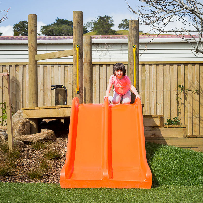 A little girl on an orange slide at Spotted Frog Preschool