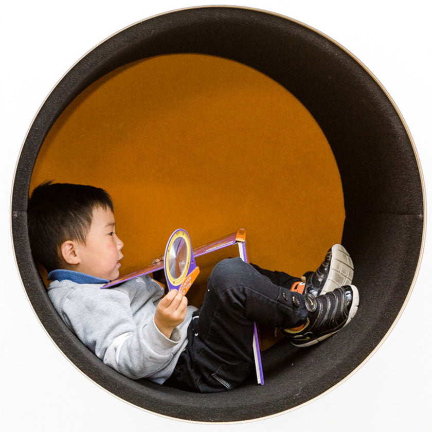 A preschool boy playing with toys in a circle tunnel at Spotted Frog Preschool
