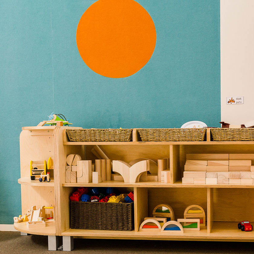 Wooden toy table against a blue wall with an orange spot at Spotted Frog Preschool